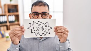 Man speaking covering his mouth depicting expletives