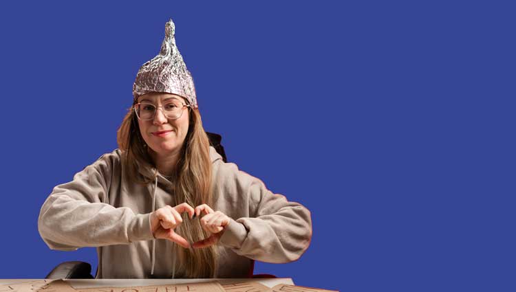 Woman with false promise making a caring heart with her hands wearing aluminum foil hat