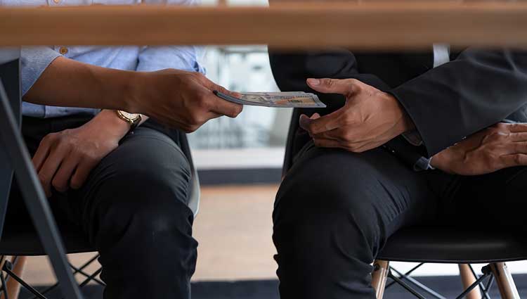 Man being bribed with cash under the table