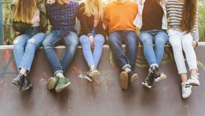 Summer holidays and teenage concept - group of smiling teenagers with skateboard hanging out outside.